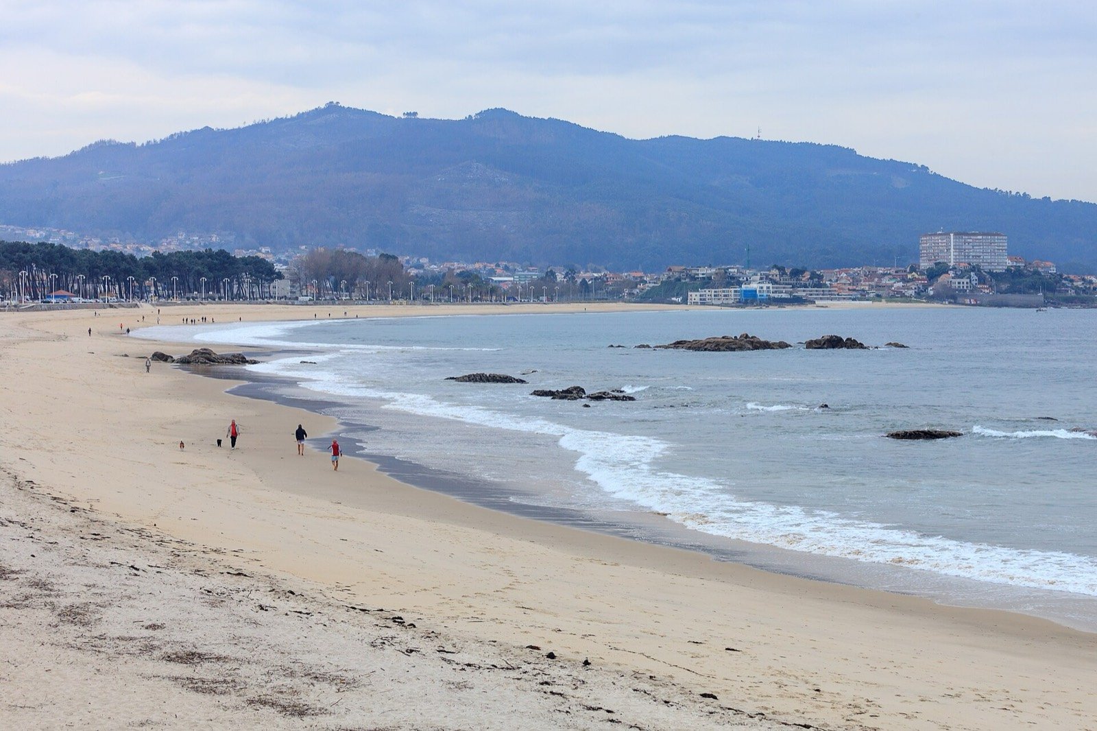 Playa de Samil en Vigo, con el arenal en curva y el monte al fondo