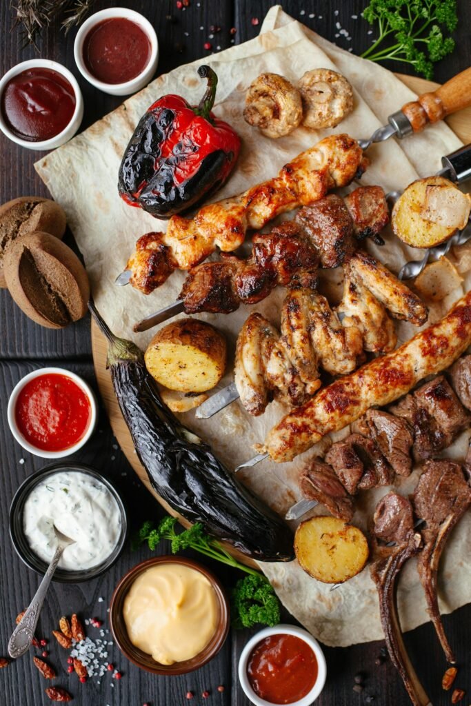 Carne a la brasa recién hecha sobre tabla de madera, con guarnición y salsas