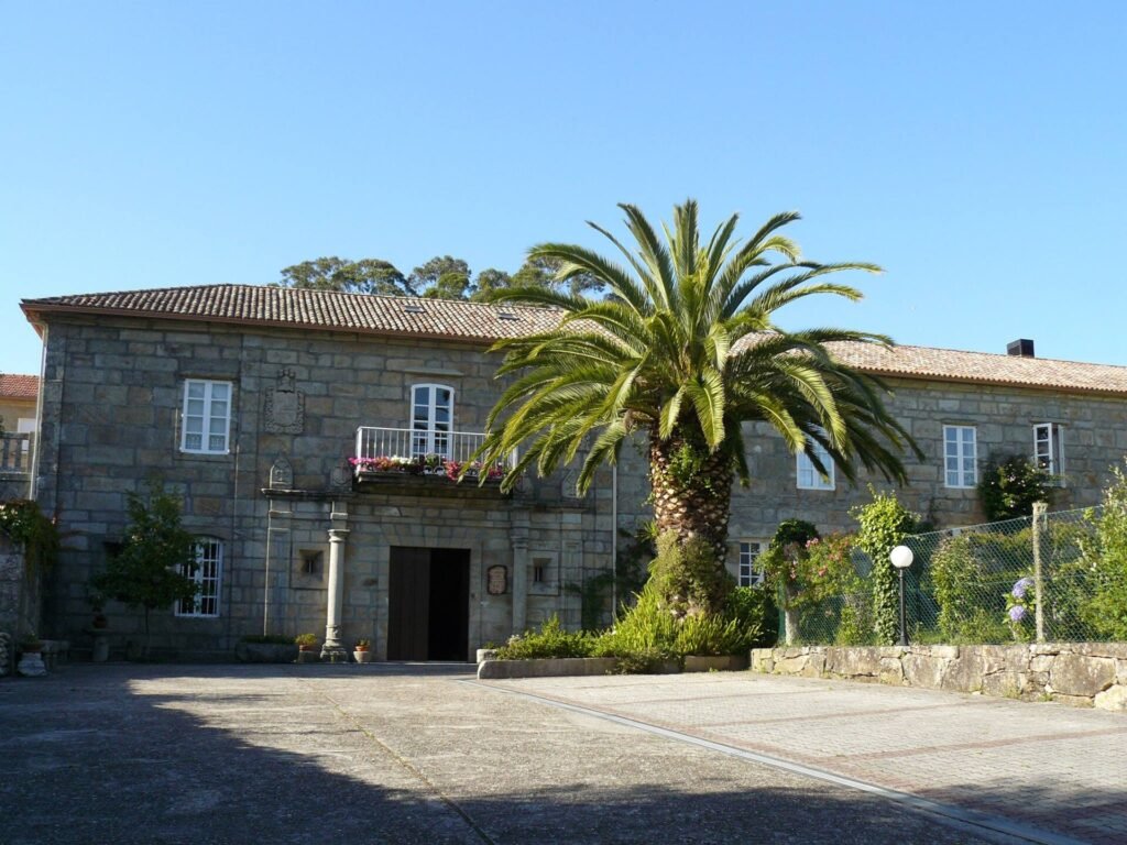 Fachada de granito del pazo de As Pías en Nigrán, con palmera y escudo nobiliario